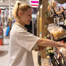 apprenant Ecofac Retail mettant le pain en rayon dans une grand surface dans le cadre de son alternance