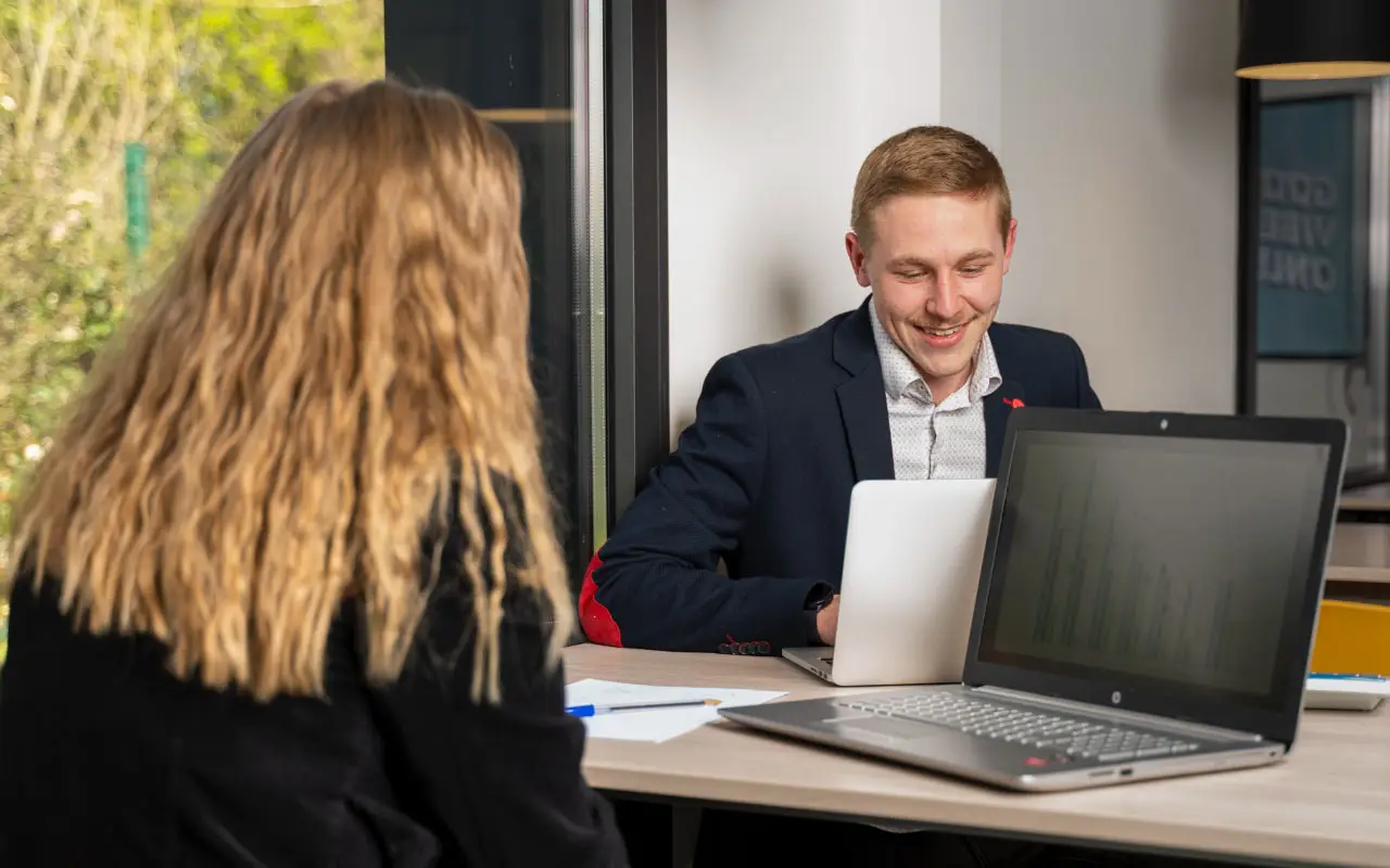 Une étudiant de dos avec un étudiant de face, tous les deux travaillant sur leur ordinateur