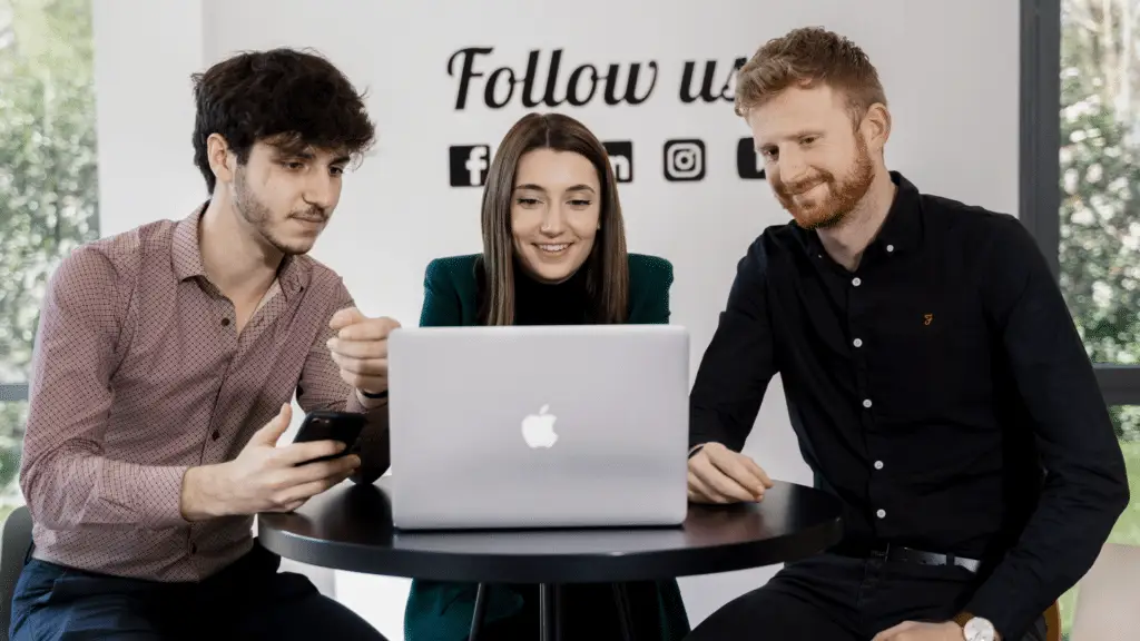 3 étudiants, deux jeunes hommes et une jeune femme, travaillant derrière leur ordinateur
