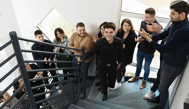 la classe Ecofac Academy applaudie un apprenant en train de monter les escaliers