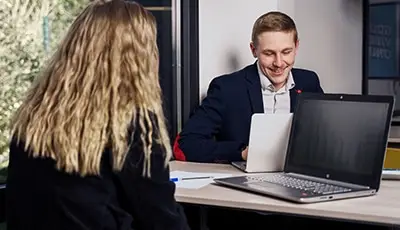 une étudiant de dos qui travaille sur son ordinateur face à un étudiant