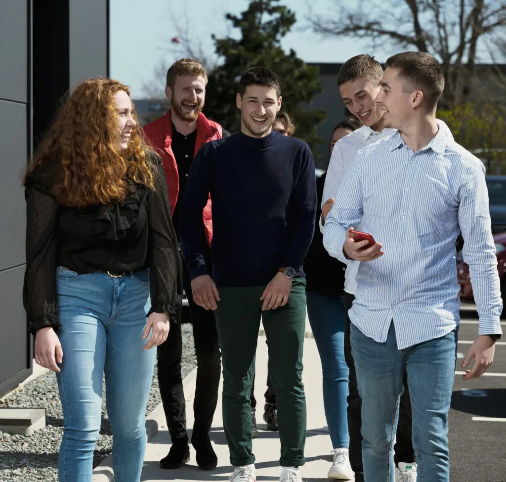 étudiant souriant en groupe qui marchent devant le campus