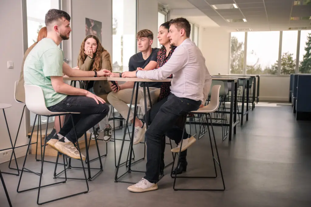 Photo de six étudiants assis autour d'une table haute pendant leur pause dans la cafétéria du campus Ecofac Rennes