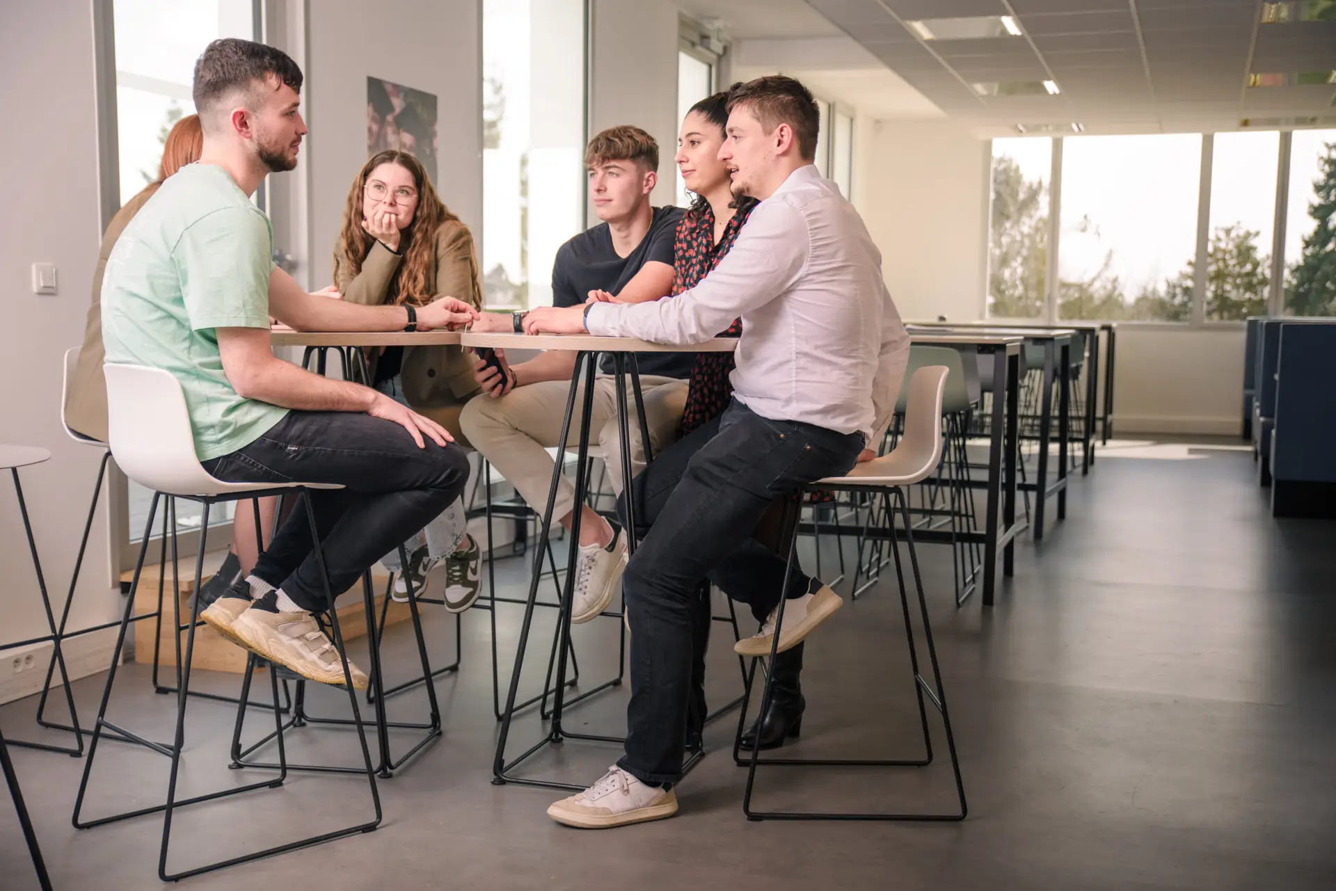 Photo de six étudiants assis autour d'une table haute pendant leur pause dans la cafétéria du campus Ecofac Rennes