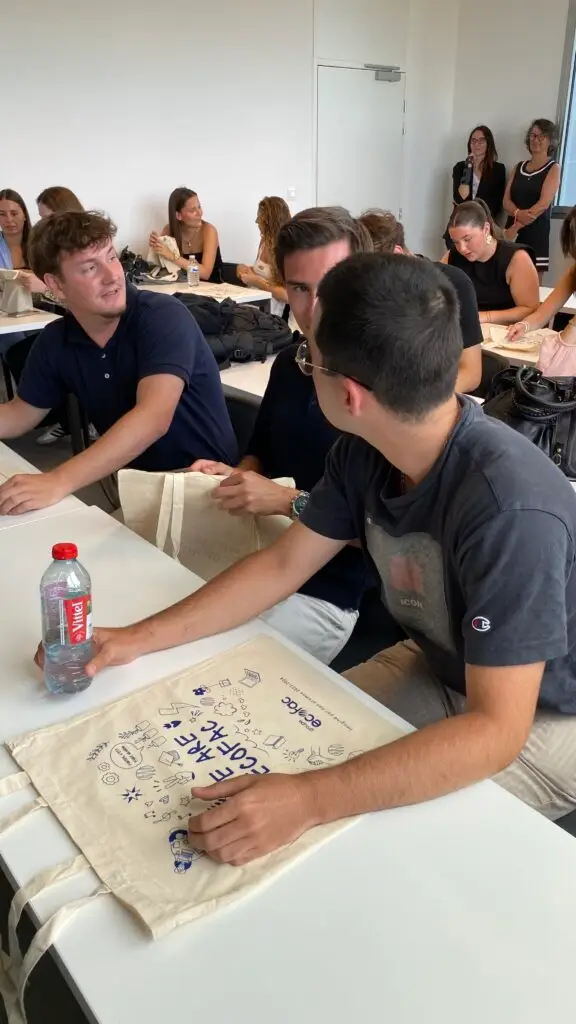 Classe qui observent les tote-bag 24/25 Ecofac, 3 jeunes hommes au premier plan qui discutent entre eux. Deux formatrices dans le fond de la salle.