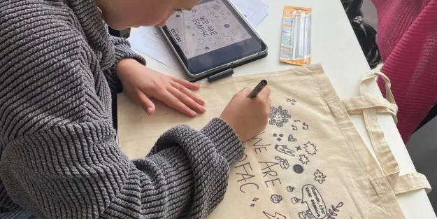 une étudiante en bts communication dessine sur un tote bag lors de l'atelier de création