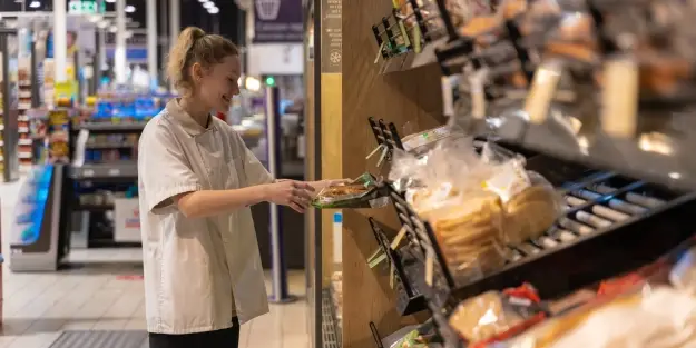 Une jeune apprenante Ecofac Retail travaille en rayon boulangerie dans une grande surface