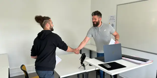 un formateur et un apprenant Ecofac Academy se serrent la main avant d'enregistrer un entretien de vente