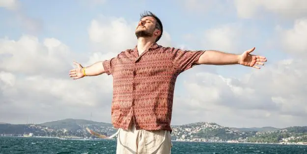homme heureux les bras ouvert devant la mer